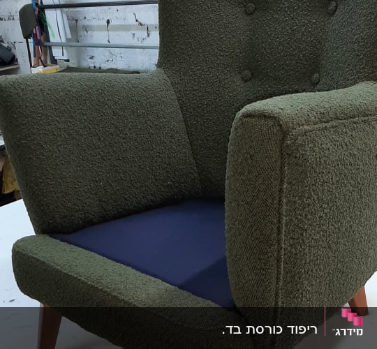 כורסה ירוקה עם ריפוד חסר על המושב